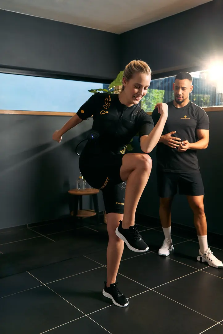 Ervaar SYMBIONT EMS-training in jouw lokale EMS-studio. Een personal trainer begeleidt een klant in een SYMBIONT EMS-pak tijdens een proefsessie in een lokaal EMS-studio. Ervaar gepersonaliseerde training, begeleiding en motivatie tijdens je EMS-proefsessie.
